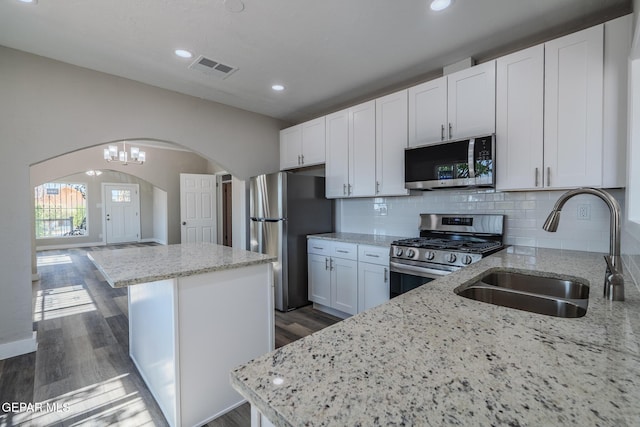 3427 Hamilton Ave, El Paso, TX 79930 - kitchen featuring appliances with stainless steel finishes, a sink, arched walkways, a center island, and light stone countertops