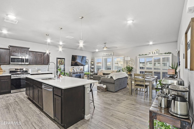 2528 Mike Price Dr, El Paso, TX 79938 - kitchen featuring appliances with stainless steel finishes, a sink, light countertops, decorative backsplash, and light wood-type flooring