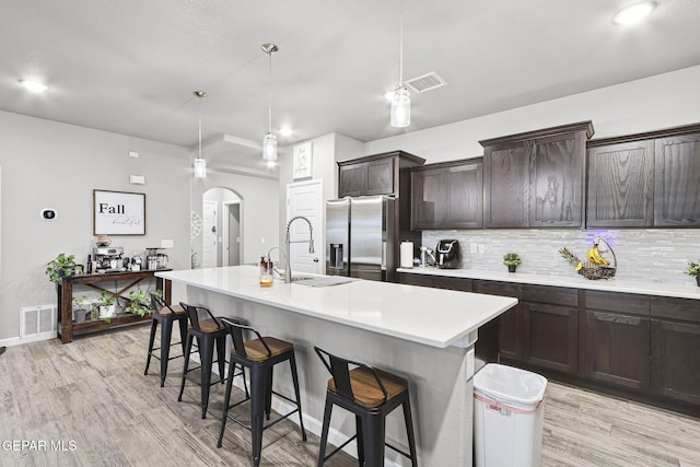 2528 Mike Price Dr, El Paso, TX 79938 - kitchen featuring stainless steel fridge, a sink, a breakfast bar, light wood-type flooring, and decorative backsplash