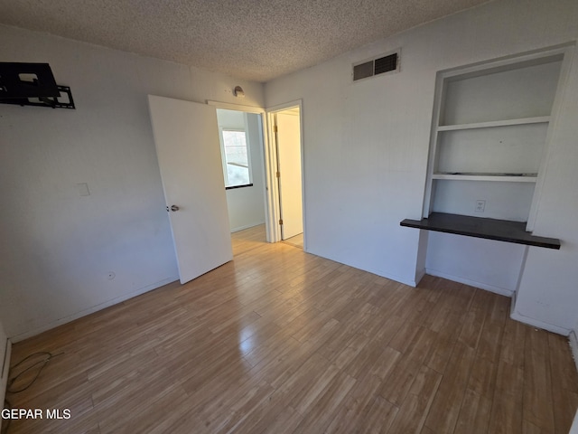 441 Irondale Dr, El Paso, TX 79912 - spare room featuring a textured ceiling, wood finished floors, and built in shelves