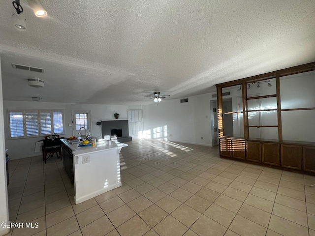 3208 Lampliter Pl, El Paso, TX 79925 - kitchen featuring a textured ceiling, a ceiling fan, light tile patterned floors, a fireplace, and open floor plan