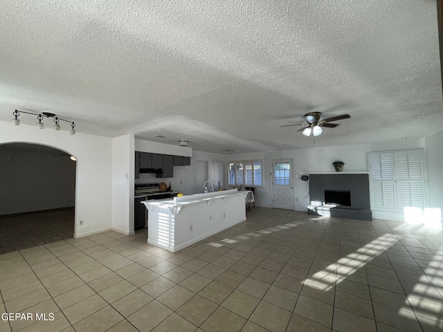 3208 Lampliter Pl, El Paso, TX 79925 - kitchen with open floor plan, light tile patterned flooring, a ceiling fan, a textured ceiling, and arched walkways