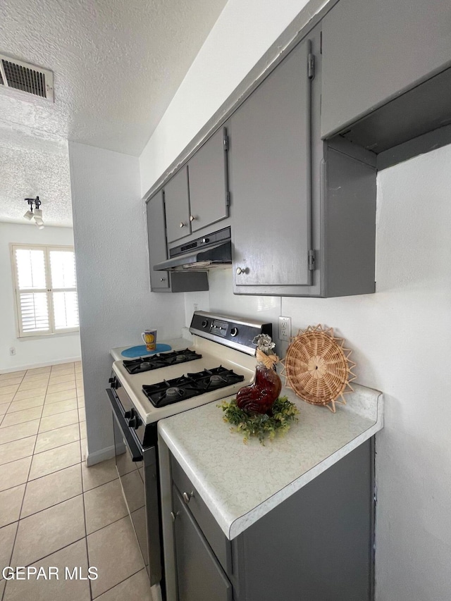 3208 Lampliter Pl, El Paso, TX 79925 - kitchen featuring range with gas stovetop, under cabinet range hood, gray cabinets, a textured ceiling, and light tile patterned flooring