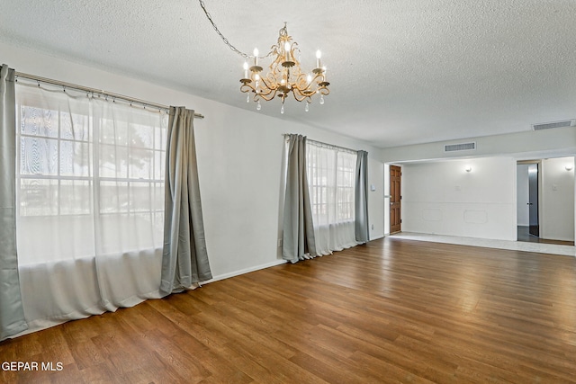 9204 Rex Ct, El Paso, TX 79925 - spare room with a chandelier, a textured ceiling, wood finished floors, plenty of natural light, and baseboards