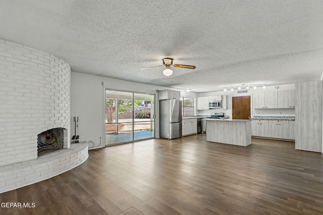 9204 Rex Ct, El Paso, TX 79925 - unfurnished living room featuring ceiling fan, track lighting, a textured ceiling, dark wood-type flooring, and a fireplace