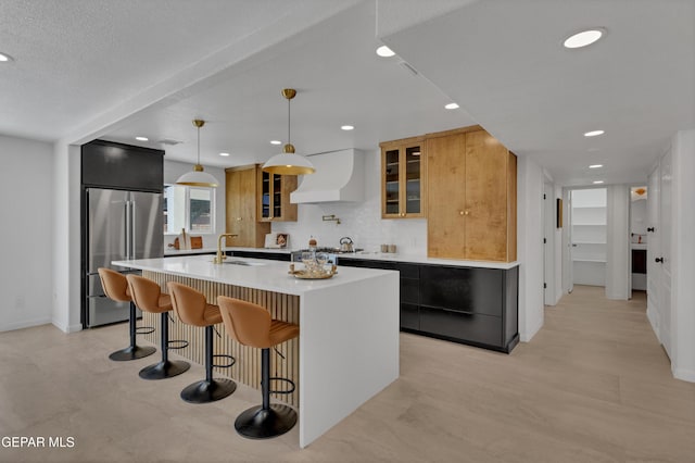 11316 Menlo Ave, El Paso, TX 79936 - kitchen featuring high quality fridge, premium range hood, a kitchen island with sink, light countertops, and glass insert cabinets