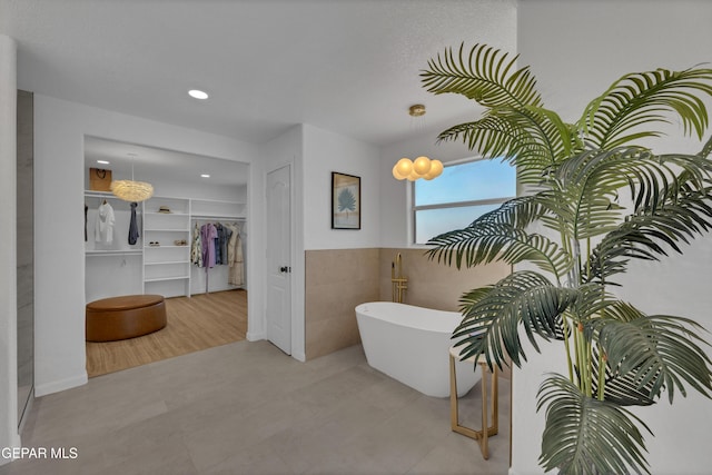 11316 Menlo Ave, El Paso, TX 79936 - full bathroom featuring a freestanding tub, a walk in closet, recessed lighting, and tile walls