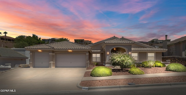 6637 Wind Ridge Dr, El Paso, TX 79912 - mediterranean / spanish home with a garage, a tile roof, driveway, and stucco siding