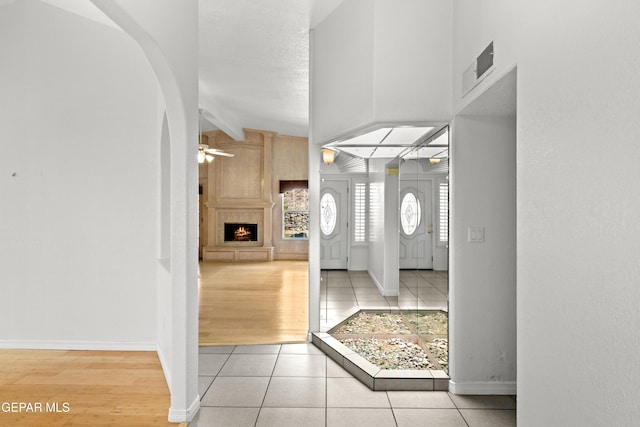 6637 Wind Ridge Dr, El Paso, TX 79912 - entryway with a fireplace, a ceiling fan, light tile patterned flooring, and arched walkways