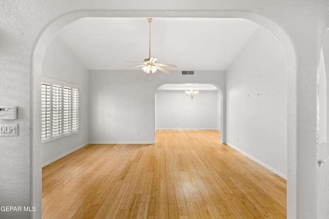 6637 Wind Ridge Dr, El Paso, TX 79912 - unfurnished room featuring arched walkways, a ceiling fan, wood finished floors, lofted ceiling, and a chandelier