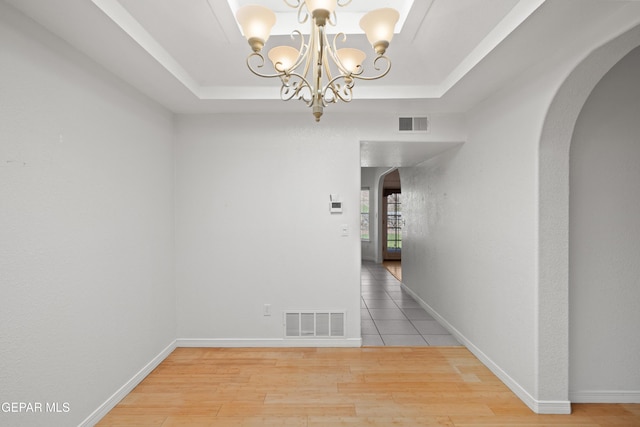 6637 Wind Ridge Dr, El Paso, TX 79912 - unfurnished dining area with arched walkways, a tray ceiling, a chandelier, and wood finished floors