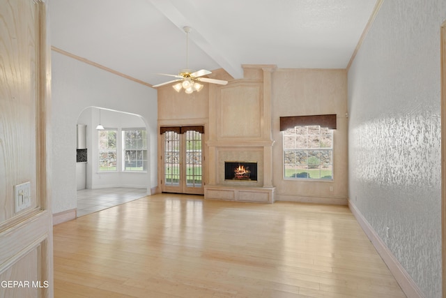 6637 Wind Ridge Dr, El Paso, TX 79912 - unfurnished living room featuring light wood-style flooring, a ceiling fan, arched walkways, a high end fireplace, and a textured wall