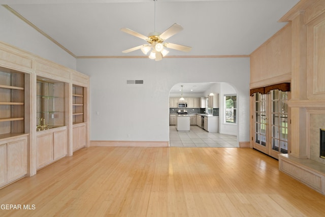 6637 Wind Ridge Dr, El Paso, TX 79912 - unfurnished living room featuring arched walkways, light wood-style floors, a tile fireplace, crown molding, and ceiling fan