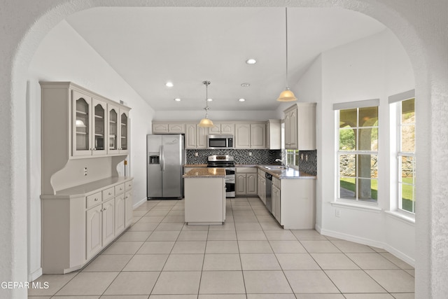 6637 Wind Ridge Dr, El Paso, TX 79912 - kitchen with appliances with stainless steel finishes, arched walkways, tasteful backsplash, light tile patterned floors, and a center island