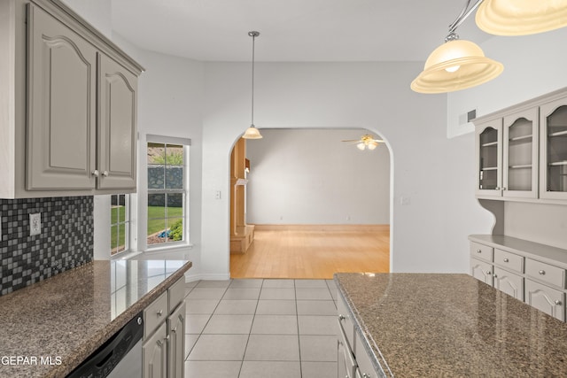 6637 Wind Ridge Dr, El Paso, TX 79912 - kitchen with arched walkways, light tile patterned floors, glass insert cabinets, decorative backsplash, and pendant lighting