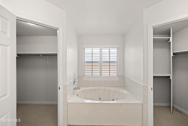 6637 Wind Ridge Dr, El Paso, TX 79912 - bathroom featuring a whirlpool tub, a walk in closet, and a textured ceiling