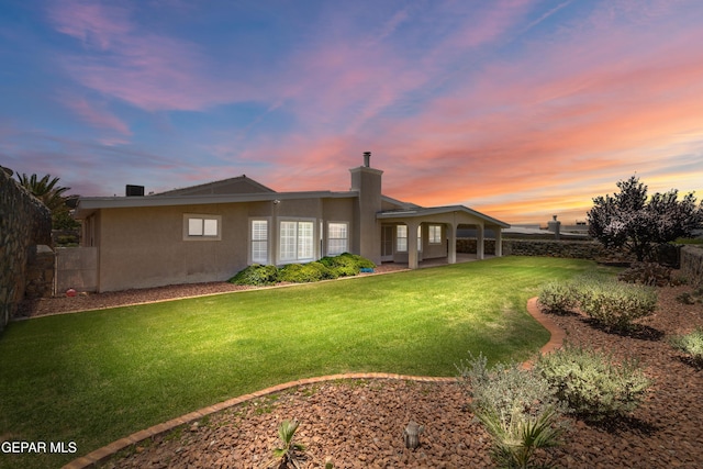 6637 Wind Ridge Dr, El Paso, TX 79912 - back of house at dusk featuring stucco siding and a chimney