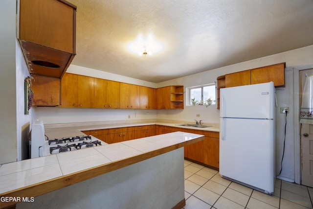113 N Moon Rd, Socorro, TX 79927 - kitchen with white appliances, open shelves, brown cabinetry, a peninsula, and light tile patterned floors