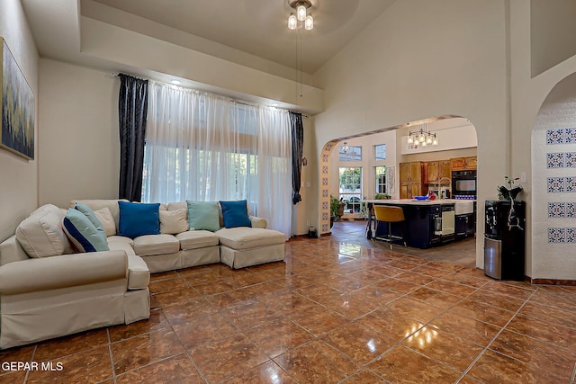 6112 Strahan Rd, El Paso, TX 79932 - living room featuring arched walkways, a towering ceiling, ceiling fan, and dark tile patterned flooring