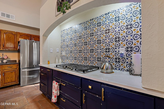 6112 Strahan Rd, El Paso, TX 79932 - kitchen with appliances with stainless steel finishes, a textured wall, stone tile floors, brown cabinets, and light countertops