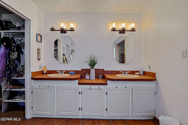6112 Strahan Rd, El Paso, TX 79932 - full bath featuring double vanity, tile patterned floors, a spacious closet, and a textured ceiling