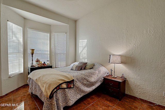 6112 Strahan Rd, El Paso, TX 79932 - tiled bedroom featuring multiple windows, a textured wall, and baseboards