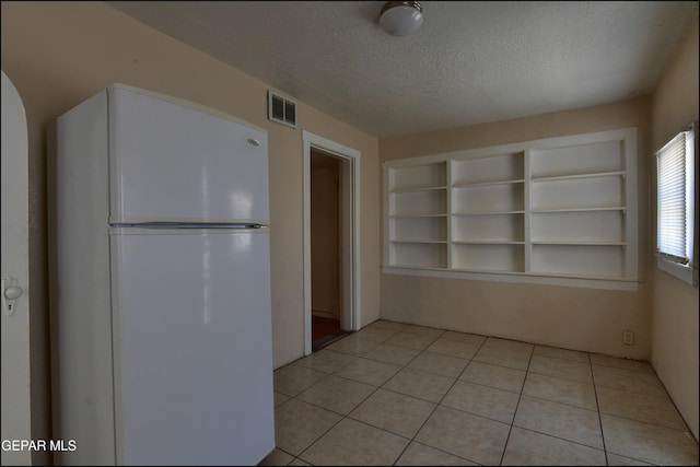 2619 Piedras St Unit A, And B, El Paso, TX 79930 - kitchen featuring freestanding refrigerator, a textured ceiling, built in features, and light tile patterned floors
