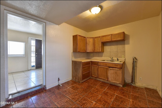 2619 Piedras St Unit A, And B, El Paso, TX 79930 - kitchen featuring light countertops, a sink, brown cabinetry, baseboards, and a textured ceiling