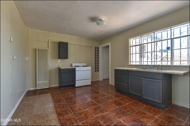 2619 Piedras St Unit A, And B, El Paso, TX 79930 - kitchen with white range with gas stovetop, a heating unit, gray cabinets, baseboards, and a textured ceiling