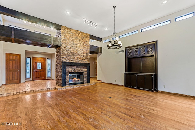 1433 Belvidere St, El Paso, TX 79912 - unfurnished living room with a high ceiling, healthy amount of natural light, wood finished floors, a fireplace, and a chandelier