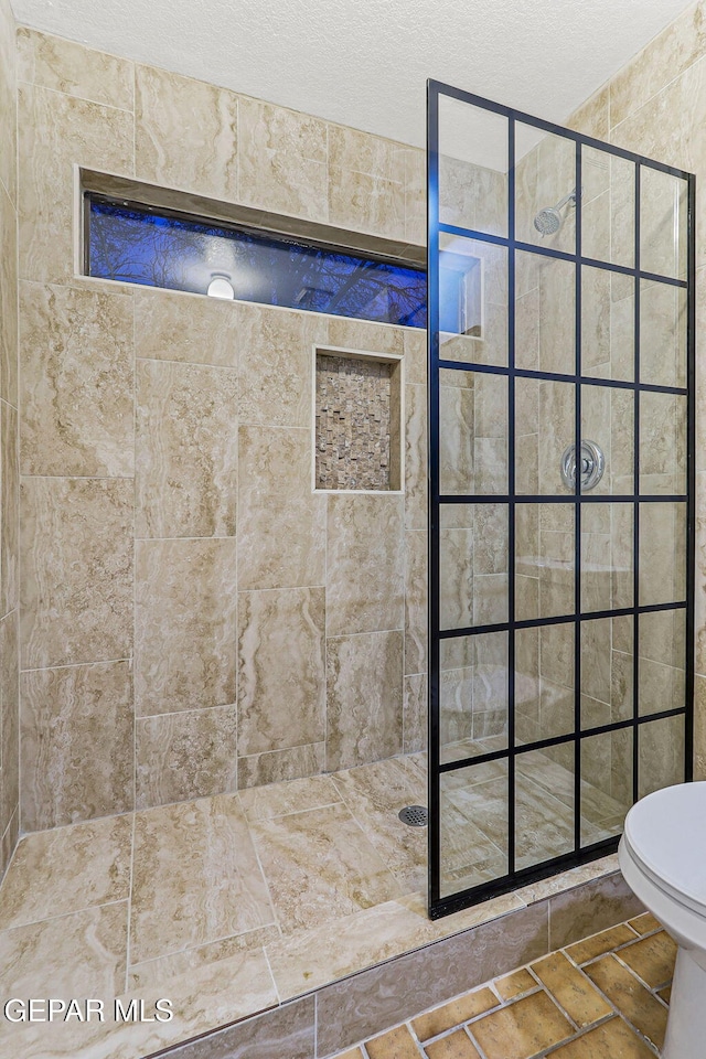 1433 Belvidere St, El Paso, TX 79912 - bathroom featuring a tile shower, toilet, and a textured ceiling