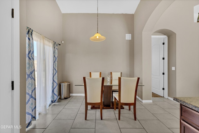 14250 Charles Pollock Ave, El Paso, TX 79938 - dining area featuring arched walkways, a towering ceiling, light tile patterned floors, and baseboards