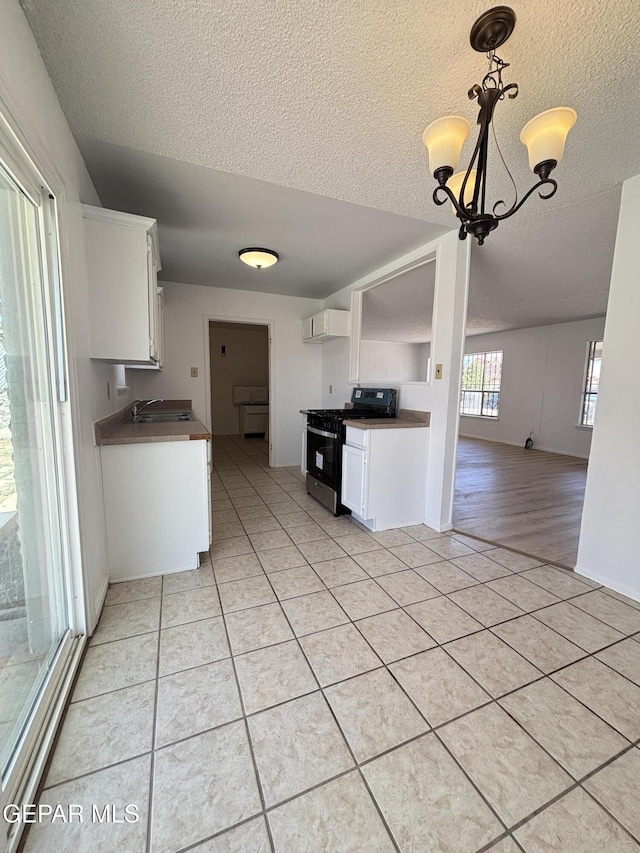5808 Dearborne Dr, El Paso, TX 79924 - kitchen with gas stove, a textured ceiling, light tile patterned flooring, white cabinetry, and a chandelier