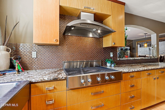 5744 Mira Grande Dr, El Paso, TX 79912 - kitchen featuring stainless steel gas stovetop, wall chimney range hood, backsplash, and arched walkways