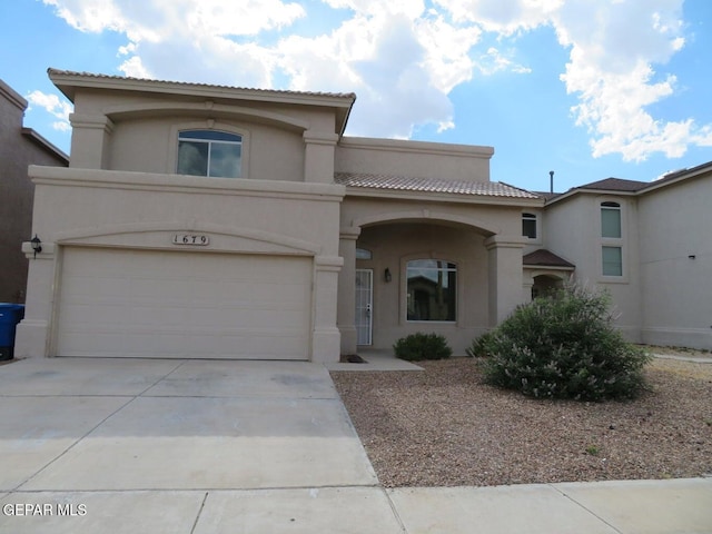 1679 Roger Bombach Dr, El Paso, TX 79936 - mediterranean / spanish-style house featuring stucco siding, concrete driveway, an attached garage, and a tiled roof
