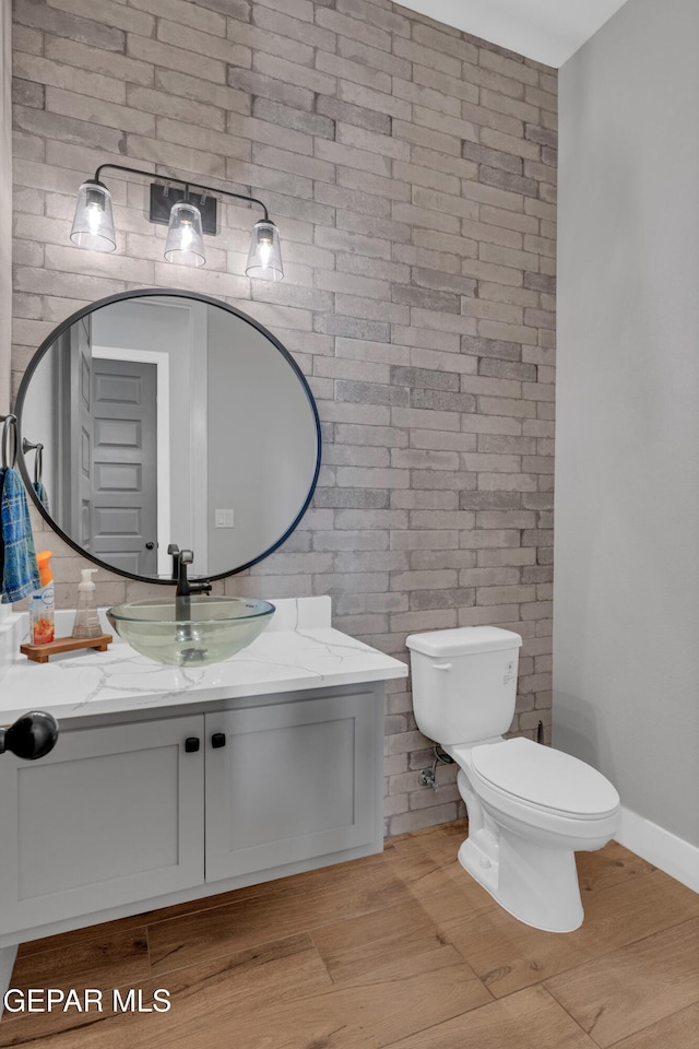 14405 Tierra Campeon, El Paso, TX 79938 - bathroom featuring brick wall, vanity, toilet, and wood finished floors