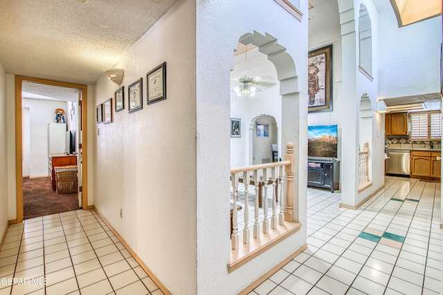 1809 Garden Gate Way, El Paso, TX 79936 - hallway featuring a textured wall, light tile patterned flooring, arched walkways, a textured ceiling, and a towering ceiling