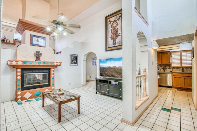 1809 Garden Gate Way, El Paso, TX 79936 - living room with ceiling fan, arched walkways, light tile patterned floors, a tiled fireplace, and a textured wall