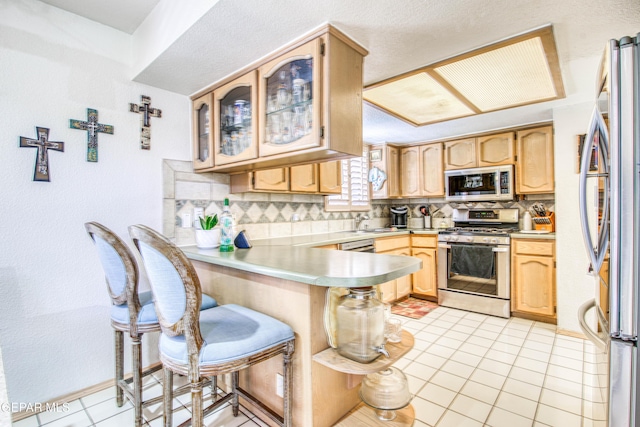1809 Garden Gate Way, El Paso, TX 79936 - kitchen with appliances with stainless steel finishes, a peninsula, tasteful backsplash, light countertops, and light brown cabinets