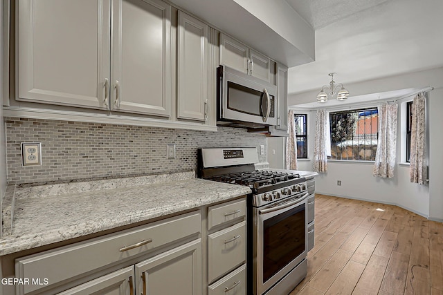 10749 Rushing Rd, El Paso, TX 79924 - kitchen featuring appliances with stainless steel finishes, a chandelier, tasteful backsplash, and light wood-style flooring