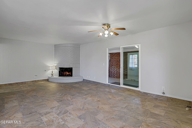 10749 Rushing Rd, El Paso, TX 79924 - unfurnished living room with a ceiling fan, stone finish floors, a fireplace, and baseboards