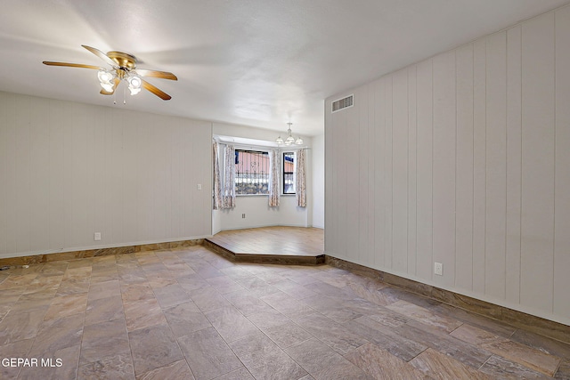 10749 Rushing Rd, El Paso, TX 79924 - spare room with a ceiling fan, wooden walls, a chandelier, and baseboards