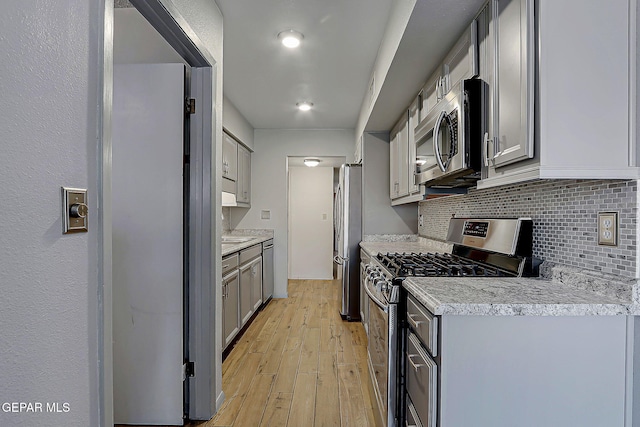 10749 Rushing Rd, El Paso, TX 79924 - kitchen featuring appliances with stainless steel finishes, light wood-style flooring, decorative backsplash, gray cabinetry, and light countertops