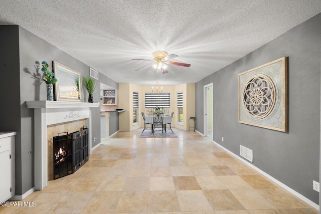 8820 Dirk Ct, El Paso, TX 79925 - living room featuring ceiling fan, a tiled fireplace, a textured ceiling, and a chandelier