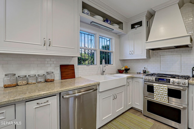818 Kerbey Ave, El Paso, TX 79902 - kitchen with appliances with stainless steel finishes, custom range hood, a sink, decorative backsplash, and crown molding