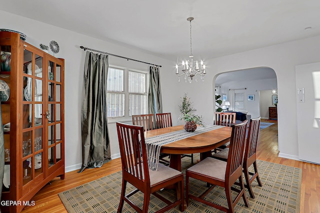 818 Kerbey Ave, El Paso, TX 79902 - dining space featuring arched walkways, light wood finished floors, and a chandelier