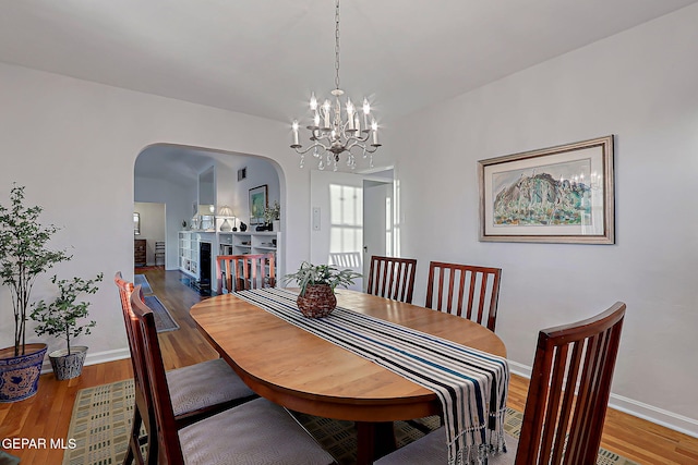 818 Kerbey Ave, El Paso, TX 79902 - dining space with arched walkways, wood finished floors, a chandelier, and baseboards