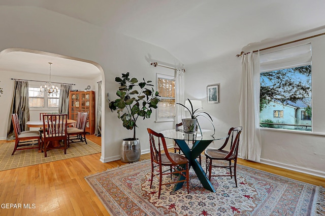 818 Kerbey Ave, El Paso, TX 79902 - dining area featuring arched walkways, a chandelier, vaulted ceiling, light wood finished floors, and baseboards