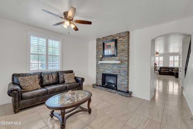 2201 Morning Mist Pl, El Paso, TX 79938 - living room with ceiling fan, arched walkways, a stone fireplace, baseboards, and light tile patterned floors