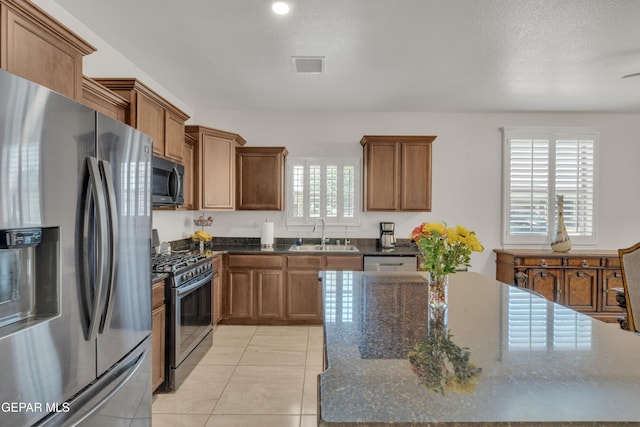 2201 Morning Mist Pl, El Paso, TX 79938 - kitchen featuring appliances with stainless steel finishes, a sink, brown cabinetry, and dark stone countertops
